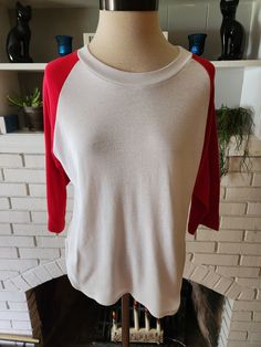 "Here is a great vintage shirt, most likely from the 80s. Feels like a poly/cotton blend. White shirt with red 3/4 length sleeves and scooped waistline at the sides. This is slightly heavier than a standard T shirt material. It's stupid soft and comfy. Feels like it's made of kitten ears. It's in incredible condition with tons of life left. Here are the measurements taken laying flat (please refer to the last pic to see how I measure shirts) Chest (armpit to armpit) 21\" Shoulder to end of sleev Red Stretch Tops With 3/4 Sleeves, Casual Red Half Sleeve Tops, Red Cotton Half Sleeve T-shirt, Red Half Sleeve Cotton T-shirt, Retro Red Crew Neck Top, Retro Red Long Sleeve T-shirt, Retro Red Long Sleeve Top, Red Retro Long Sleeve Top, Retro Red Crew Neck Shirt