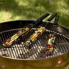 three grill tongs sitting on top of an open bbq with food cooking in it