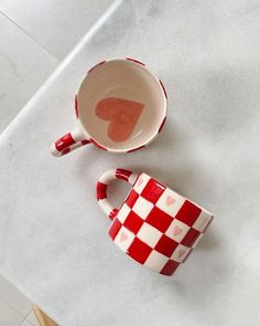 two red and white checkered cups sitting on top of a counter next to each other