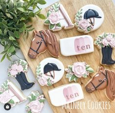 decorated cookies with horse heads and flowers on a cutting board next to a potted plant