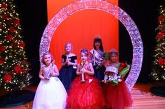 the children are posing for a photo in front of christmas trees and decorations on stage