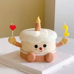 a birthday cake with a candle in the shape of a cartoon character holding a heart