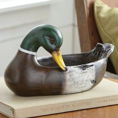 a statue of a duck in a bowl on top of a book