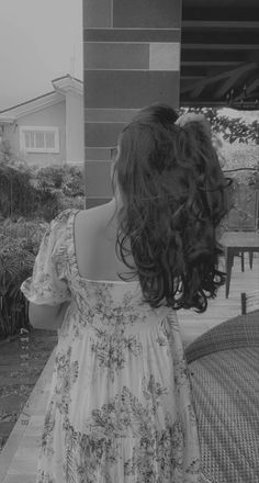 the back of a woman's head as she walks down a sidewalk with her hair blowing in the wind