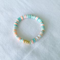 a close up of a beaded bracelet on a white surface with blue and orange beads