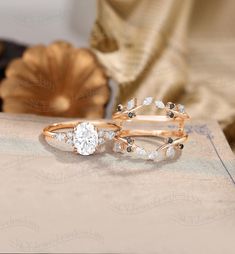 two wedding rings sitting on top of a table next to a flower shaped vase with flowers in it