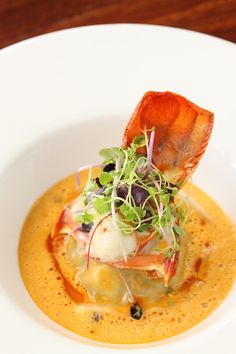 a white bowl filled with food and garnished in sauce on top of a wooden table