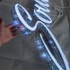 a hand is holding a lit up coca cola sign