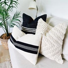 two black and white pillows sitting on top of a couch next to a potted plant