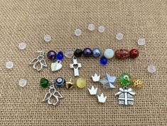 several different colored beads and charms laying on a tablecloth with white circles around them