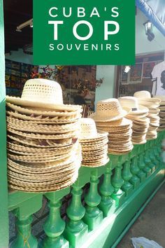 several hats are stacked on top of each other in front of a store window with the words cuba's top souvenirs