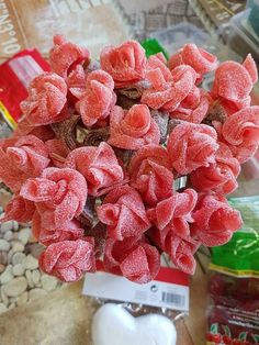 a bouquet of pink flowers sitting on top of a table next to some candy bags