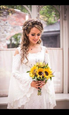 a woman in a white dress holding a bouquet of sunflowers