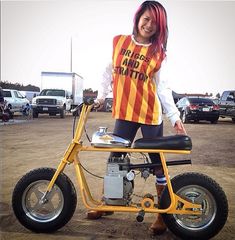 a woman standing on top of a small motorcycle