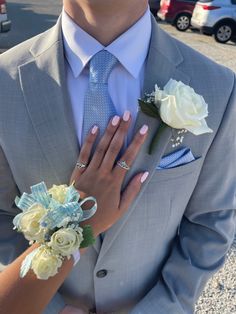 a man in a suit and tie with flowers on his lapel holding the woman's hand