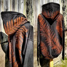 an orange and black hoodie is hanging on a wooden fence