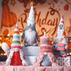 three gnome figurines sitting on top of a birthday cake with candles in the middle