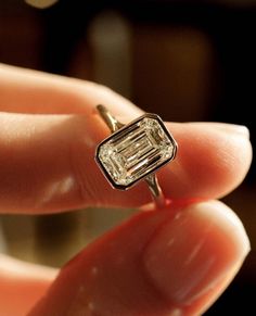 a close up of a person's hand holding a ring with a diamond in it