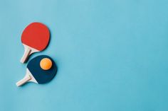 two ping pong paddles and an orange ball on a blue background