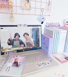 an open laptop computer sitting on top of a desk next to a bunch of books