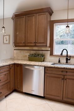 a large kitchen with wooden cabinets and marble counter tops, along with a dishwasher