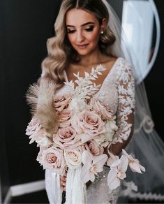 a woman in a wedding dress holding a bouquet of pink roses and feathered bridals