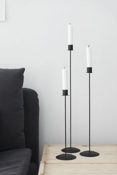 three black candles are on a table next to a couch