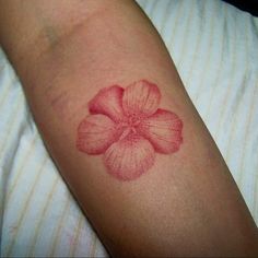 a red flower tattoo on the arm