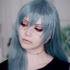 a woman with long blue hair and piercings on her face is looking at the camera