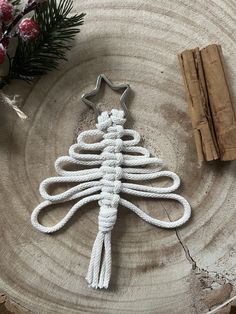 a white rope christmas tree ornament sitting on top of a piece of wood