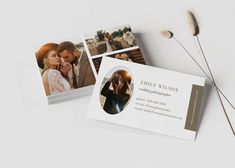 two business cards sitting next to each other on top of a white table with dried flowers