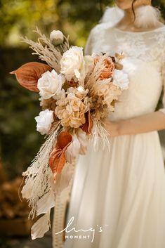 a woman in a white dress holding a bouquet of flowers and feathers on her wedding day