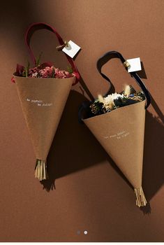 two paper cones with flowers in them on a brown surface