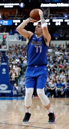 a man holding a basketball on top of a wooden floor in front of a crowd