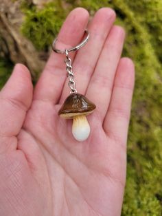 a hand holding a tiny brown and white mushroom keychain