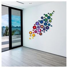 a white wall with colorful circles on it in front of a glass door and large window