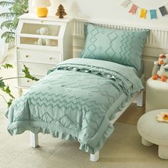 a child's bed with blue comforter and pillows in a white bedroom setting