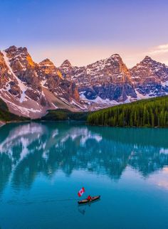 a small boat floating on top of a lake surrounded by mountains