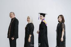 a group of people standing next to each other in graduation robes and gowns, all smiling at the camera