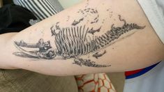 a person with a tattoo on their arm that has a skeleton and fish in it