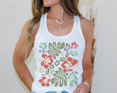 This hibiscus flower racerback tank top is the perfect tropical tank for summer!  Perfect to wear for a vacation, a trip to the pool or the beach, or for every day wear! This is a slim fit tank and runs smaller than usual.  Please use the size chart in the photos to determine your best fit and measure seam to seam.  * Q U I C K * F A C T S * ✺ Material: 60% combed ring-spun cotton, 40% polyester ✺ Extra light fabric ✺ Slim fit ✺ Runs smaller than usual ✺ Turn inside out and wash and dry low heat.  Do not iron decoration. ✺ Colors may vary due to computer monitors and printing inks. ✺ While we offer several shirt colors some may have a better contrast with the design. Keep that in       mind when choosing your color.  * S I Z I N G * ✺ Size guide and fit: Please see size charts in photos fo Floral Print Tank Top For Vacation, Casual Beach Tank Top With Floral Print, Casual Floral Print Tank Top For Beach, Casual Sleeveless Tropical Print Tank Top, Casual Sleeveless Tank Top With Tropical Print, Sleeveless Floral Print Tops For Vacation, Summer Sleeveless Hawaiian Tops, Tropical Summer Tank Top, Summer Hawaiian Sleeveless Tops