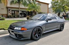 a gray sports car parked in front of a building with palm trees on the street