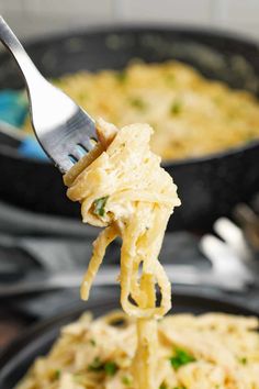 a fork full of pasta being lifted from a skillet