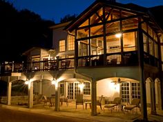 an outside view of a house at night with lights on the porch and patio furniture