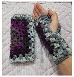 someone is holding their hand on top of a crocheted blanket