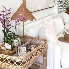 a wicker basket with flowers and pictures on it in front of a white couch