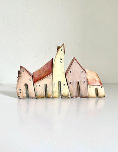 a group of small wooden houses sitting on top of a white table next to a wall