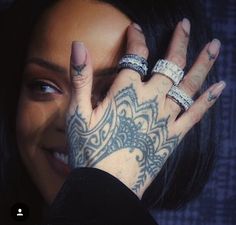 a close up of a person with tattoos on their hands and fingers, covering her face