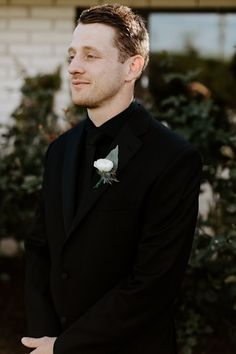 a man in a tuxedo looks off into the distance with his hand on his hip