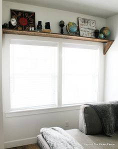 a couch sitting under a window in a living room next to a wall mounted clock